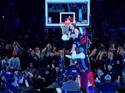 Mac McClung hace un mate saltando sobre el exjugador Shaquille O'Neal durante la competición de mates durante la noche del sábado del All Star de la NBA en el Lucas Oil Stadium.