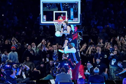 Mac McClung hace un mate saltando sobre el exjugador Shaquille O'Neal durante la competición de mates durante la noche del sábado del All Star de la NBA en el Lucas Oil Stadium.