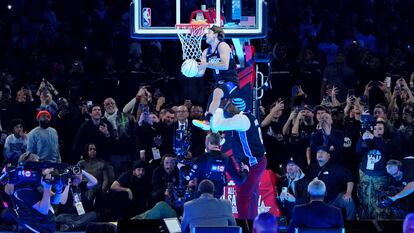 Mac McClung hace un mate saltando sobre el exjugador Shaquille O'Neal durante la competición de mates durante la noche del sábado del All Star de la NBA en el Lucas Oil Stadium.