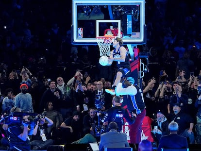 Mac McClung hace un mate saltando sobre el exjugador Shaquille O'Neal durante la competición de mates durante la noche del sábado del All Star de la NBA en el Lucas Oil Stadium.