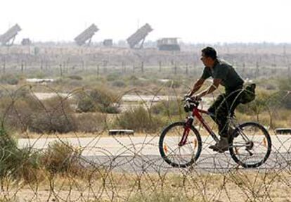 Un soldado británico pasea ayer en bicicleta por su base, en Kuwait, con las baterías de Patriot al fondo.