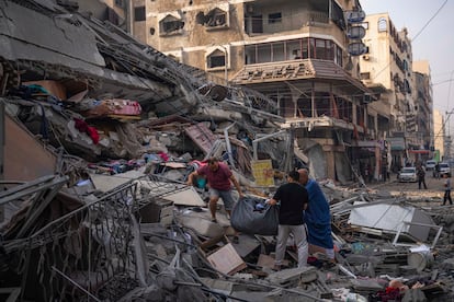 Palestinos rescatan objetos de un edificio colapsado tras un ataque israelí el domingo en Gaza.