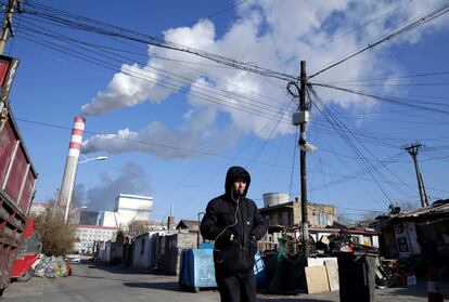 Un hombre camina, en noviembre de 2019, frente a una planta de generación de electricidad a partir de carbón en Harbin (China).