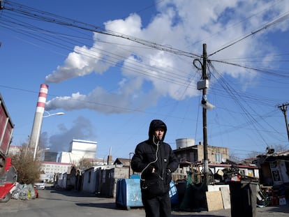 Un hombre camina, en noviembre de 2019, frente a una planta de generación de electricidad a partir de carbón en Harbin (China).