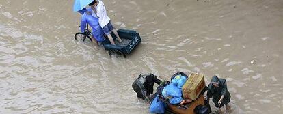 Vecinos de la provincia china de Zhejiang intentan desplazarse en calles inundadas por el paso de Wipha.