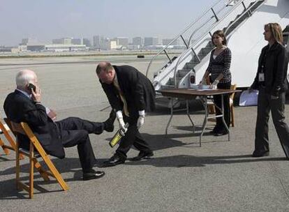 Miembros del equipo de seguridad comprueban los zapatos del senador John McCain antes de subir al avión en Los Ángeles.