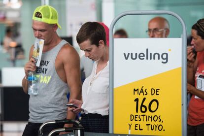 Pasajeros hacen cola ante el check-in de Vueling en el aeropuerto de El Prat.