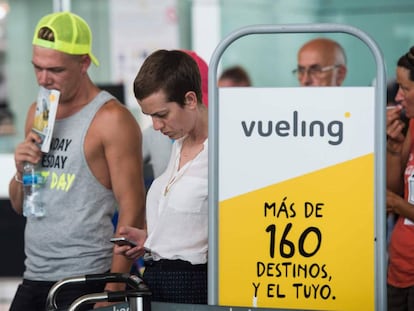 Pasajeros hacen cola ante el check-in de Vueling en el aeropuerto de El Prat.