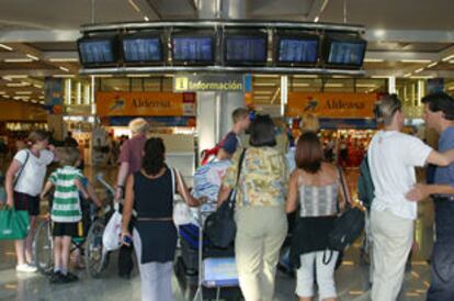 Varias personas observan el panel de horarios del aeropuerto de Mallorca, que sufrió graves retrasos.