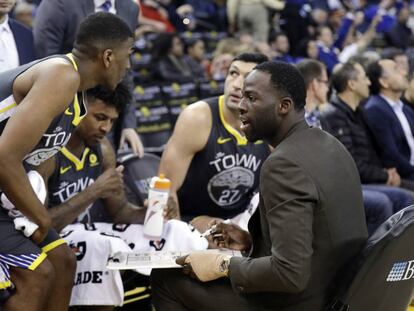 Draymond Green, lesionado, da instrucciones en el banquillo.