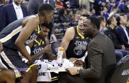 Draymond Green, lesionado, da instrucciones en el banquillo.