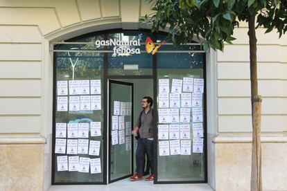 La porta d'una oficina de Gas Natural empaperada de cartells contra la pobresa energètica.