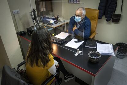 El educador social Agustí Sapinya escucha tras la mampara a Lidia (nombre supuesto) en la oficina de atención a la víctima de Sueca.  