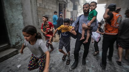 Un grupo de palestinos, entre ellos varios niños, corren por una calle en Gaza este lunes tras un bombardeo israelí.