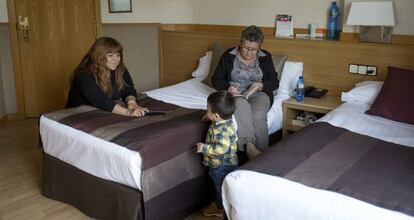 Carina juega con su hijo Gorka en presencia de Pepa, su vecina, en la habitación de hotel donde viven realojadas.