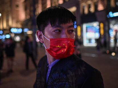 Un hombre se protege con una mascarilla con los colores de la bandera china en una calle de Shanghái