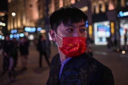 Un hombre se protege con una mascarilla con los colores de la bandera china en una calle de Shanghái