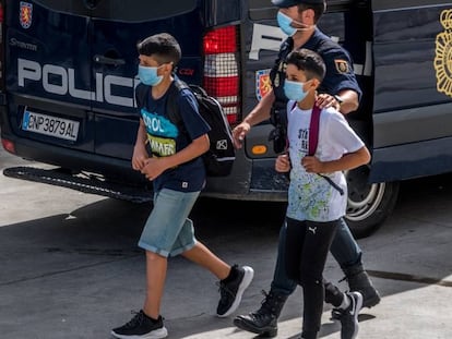 Un policía acompaña a dos menores, el pasado 20 de mayo, en Ceuta.
