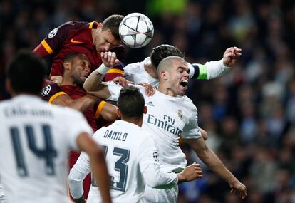 Edin Dzeko  cabecea el balón en medio del marcaje de Pepe y Sergio Ramos. 