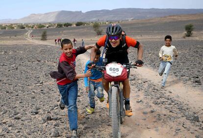 Un competidor es ayudado por unos niños mientras monta su bicicleta durante la Etapa 3 de la 13ª edición de Titan Desert 2018, el 1 de mayo de 2018.