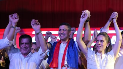 El presidente electo del Partido Colorado, Santiago Peña, celebra su victoria junto a su esposa, Leticia Ocampos, y el expresidente Horacio Cartes en Asunción el 30 de abril de 2023.