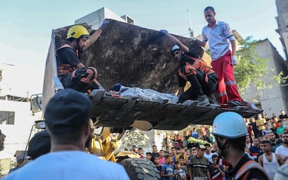 Trabajadores de emergencias trasladaban con una excavadora el cuerpo de una persona atrapada entre los escombros de un edificio tras un bombardeo, este sábado en Jan Yunis, al sur de la franja de Gaza. 