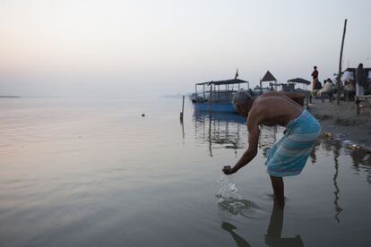 Un indio hindú toca el agua del río Ganges a su paso por Brijghat (India).