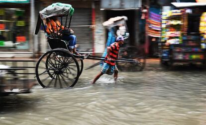 Un conductor de bicitaxi atraviesa una calle inundada en Calcuta, India.