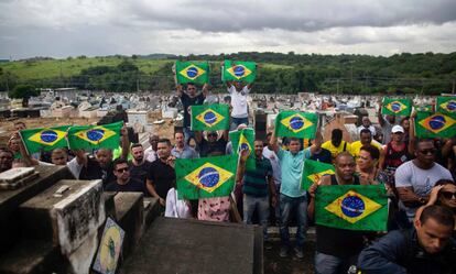 Manifestantes levam bandeiras do Brasil sujas de tinta vermelha em protesto no cemitério Ricardo de Albuquerque. no Rio, no último dia 10, contra a ação do Exército que causou duas mortes.