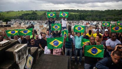 Manifestantes levam bandeiras do Brasil sujas de tinta vermelha em protesto no cemitério Ricardo de Albuquerque. no Rio, no último dia 10, contra a ação do Exército que causou duas mortes.