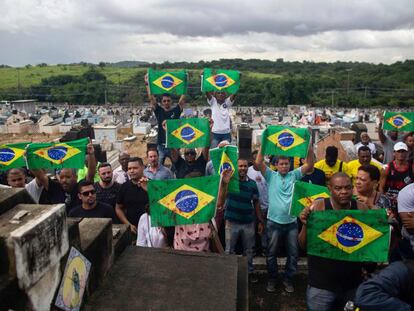 Manifestantes levam bandeiras do Brasil sujas de tinta vermelha em protesto no cemitério Ricardo de Albuquerque. no Rio, no último dia 10, contra a ação do Exército que causou duas mortes.