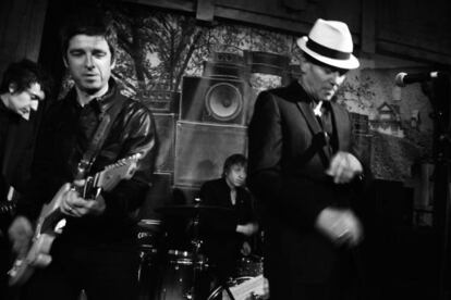 Noel Gallagher, a la izquierda con una guitarra, toca en el escenario con Paul Simonon, con sombrero, en su fiesta de cumpleaños en un bar del centro de Londres.