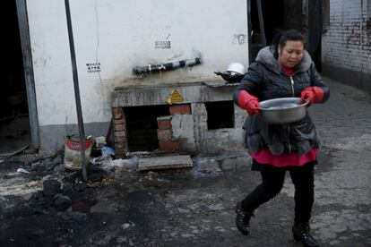 Una trabajadora migrante lleva agua de una fuente comunitaria para beber y cocinar en un poblado de trabajadores inmigrantes en Pekín (China).