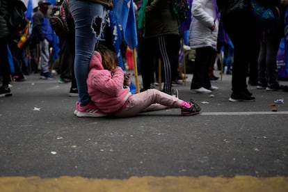 Una niña usa el móvil mientras descansa a los pies de su madre, durante la protesta.