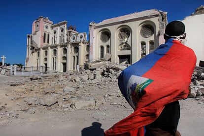 Un haitiano ondea la bandera a su paso junto a las ruinas de la catedral, destruida durante el terremoto.