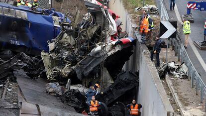 Workers supported by a crane try to remove debris from the rail lines after a collision in northern Greece.