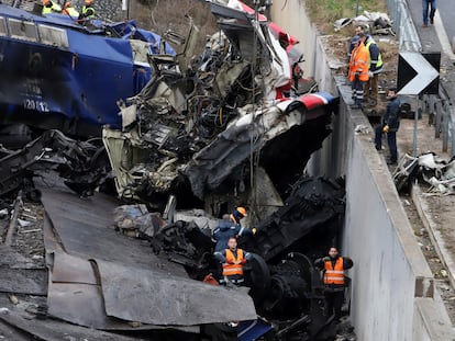 Workers supported by a crane try to remove debris from the rail lines after a collision in northern Greece.