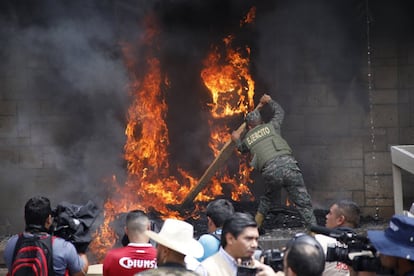 Un soldado intenta apagar el fuego que protestantes habían iniciado en la entrada principal de la Embajada norteamericana.