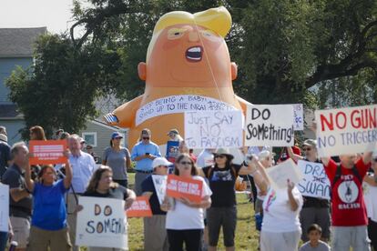 Manifestantes anti-Trump se reúnen ante un gigantesco monigote que caricaturiza al presidente poco antes de su llegada a Dayton.
