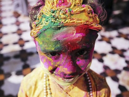 Una niña, totalmente cubierta de polvo de colores, sonríe a cámara disfrazada del dios hindú Krishna