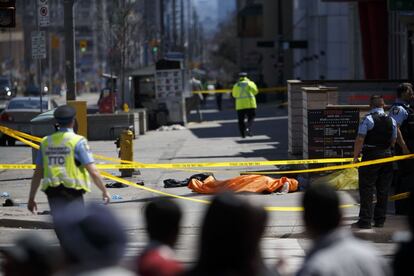 Una lona cubre un cuerpo después de que una camioneta se estrellara contra los varios peatones en Toronto, Canadá.