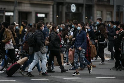 Desenes de persones creuen el pas de vianants que comunica la plaça Catalunya amb la Rambla a Barcelona.