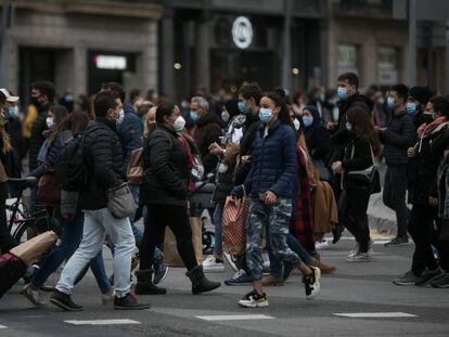 Desenes de persones creuen el pas de vianants que comunica la plaça Catalunya amb la Rambla a Barcelona.