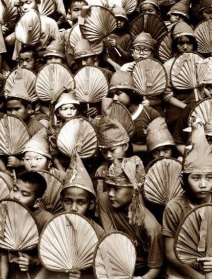 Ni&ntilde;os de una escuela de Bangkok contemplando un partido de baloncesto, ataviados con gorros de papel que se hab&iacute;an fabricado ellos mismos.