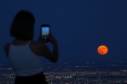 A woman takes a picture as a super moon, known as the Blue Moon, rises above Ciudad Juarez, Mexico August 30, 2023