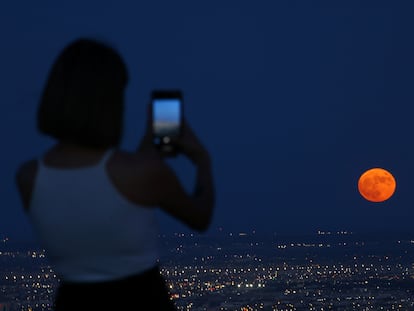 A woman takes a picture as a super moon, known as the Blue Moon, rises above Ciudad Juarez, Mexico August 30, 2023