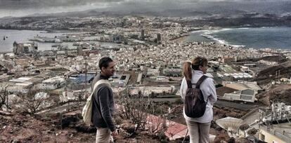 Dos excursionistas contemplan Las Palmas de Gran Canaria, con el barrio de La Isleta en primer plano.