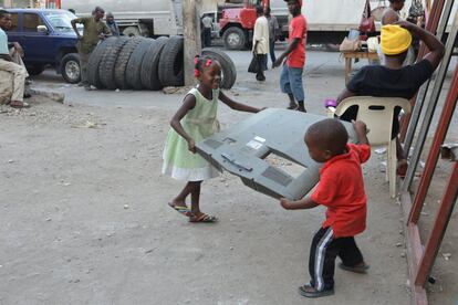 In this April 4, 2016 photo, children play with a piece of a broken television outside sculptor Andre Eugene\x92s open-air museum and art workshop off a trash-strewn street cutting through some of the poorest neighborhoods in Port-au-Prince, Haiti. Andre Eugene a founding member of a loose collective of Haitian artists called Atis Rezistans who have become celebrated in the international art world by creating sculptures out of scrapped car parts, old wood, discarded toys and even human skulls found scattered outside crumbling mausoleums. (AP Photo/David McFadden)