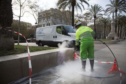 Un trabajador municipal limpia una pintada en el mobiliario urbano del paseo de Llu&iacute;s Companys de Barcelona.