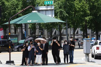 Personas con mascarillas esperan para cruzar una calle de Seúl.